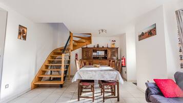 A dining area with a wooden staircase, a dining table, chairs, and a sofa.