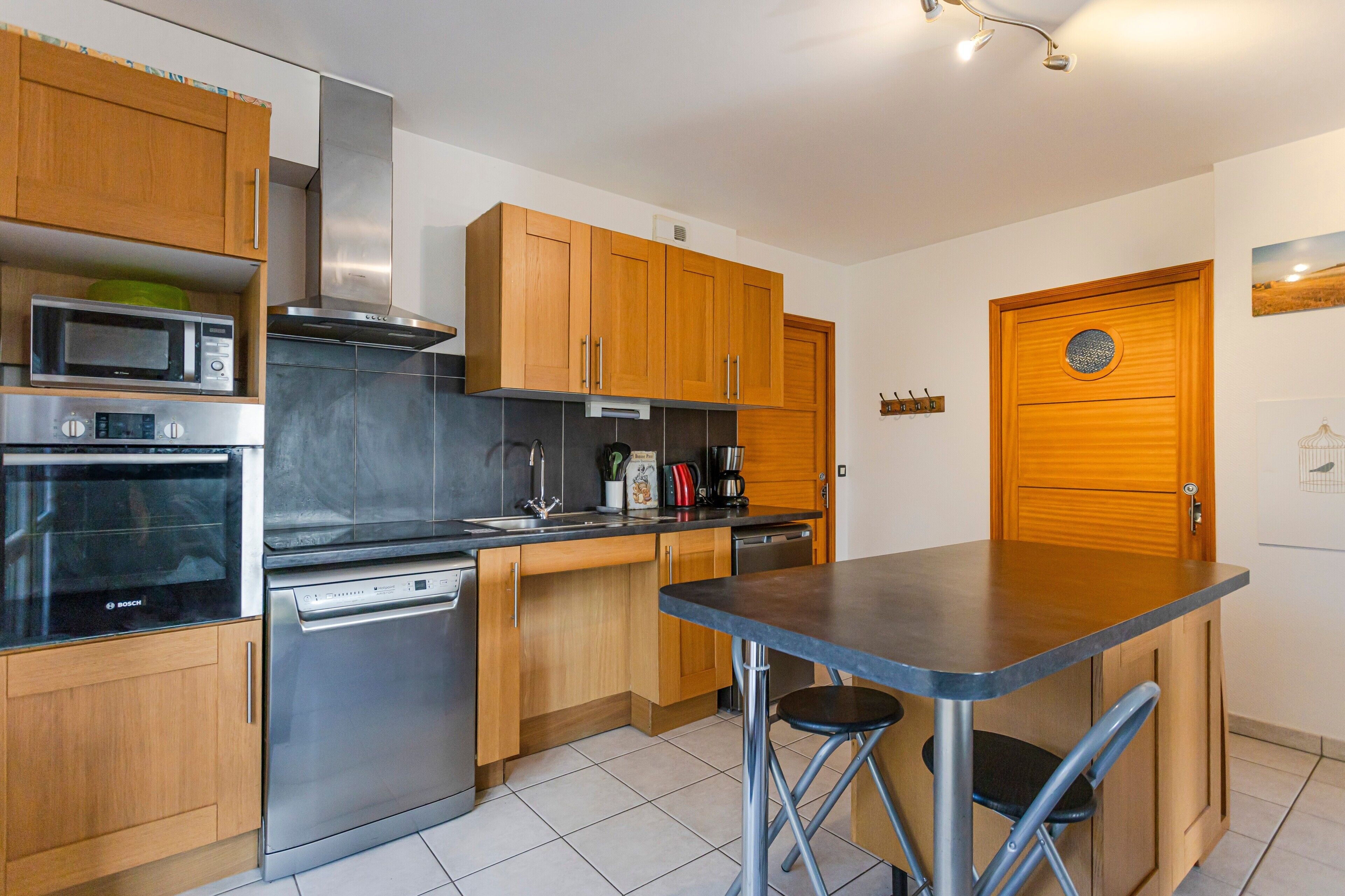 A modern kitchen with wooden cabinets, stainless steel appliances, and a bar area.