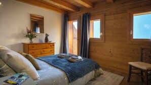 Un dormitorio con cama, cómoda, silla y ventana.