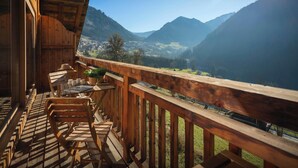 Un balcón de madera con vistas a un valle y montañas.