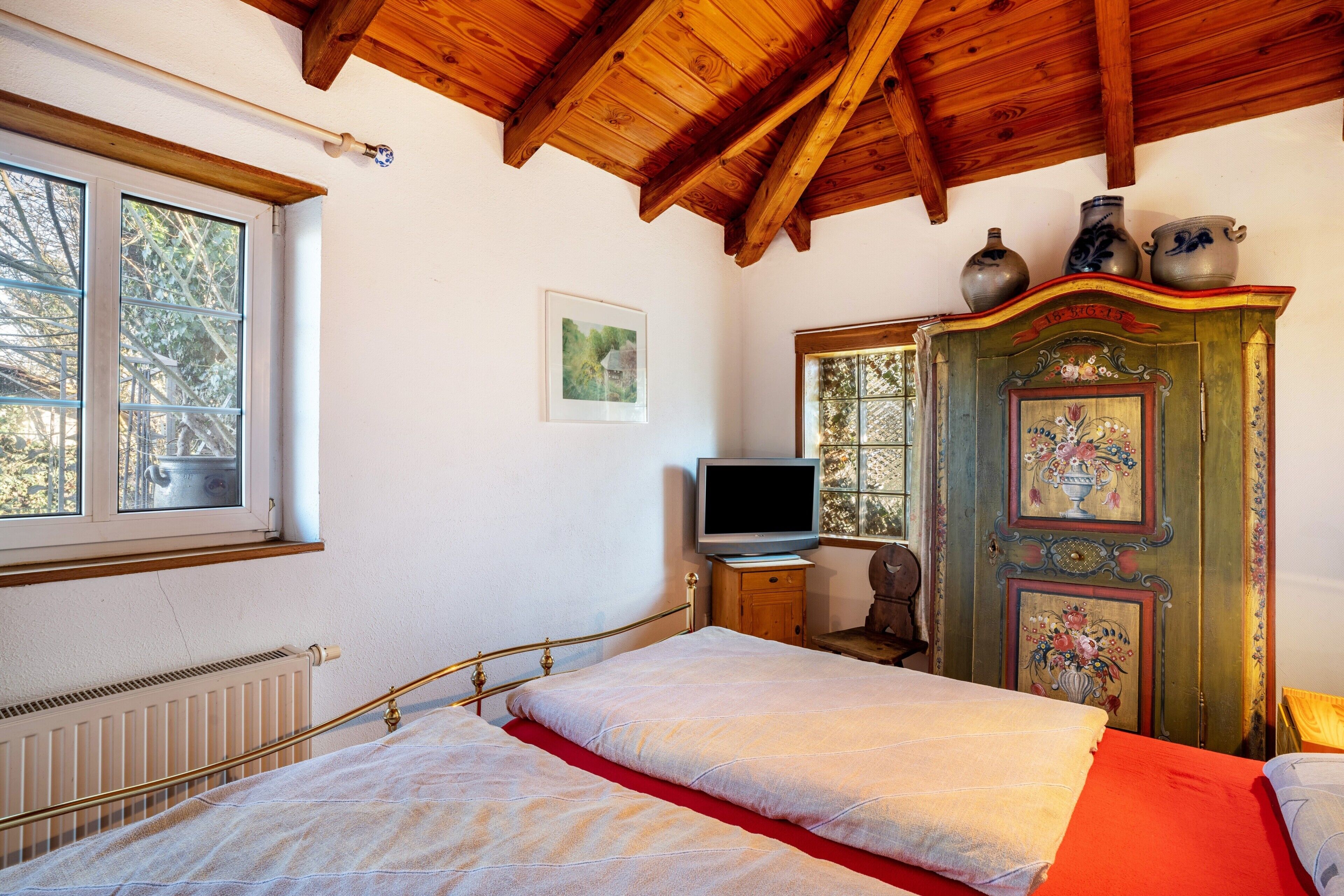 A bedroom with a bed, a television, a dresser, and a window.