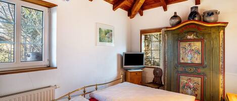 A bedroom with a bed, a television, a dresser, and a window.