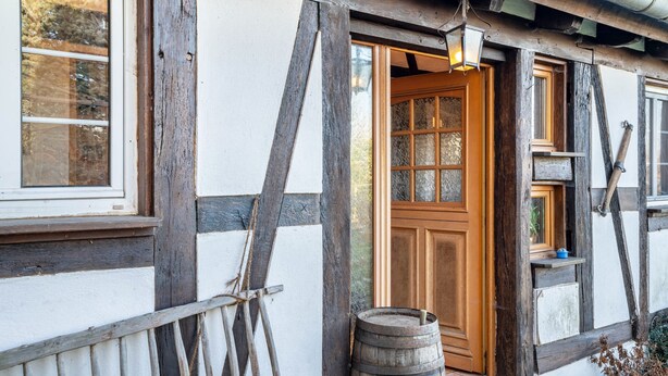 Ein traditionelles Gebäude mit einer Holztür, einem Fenster mit Holzrahmen und einem Fassade davor.