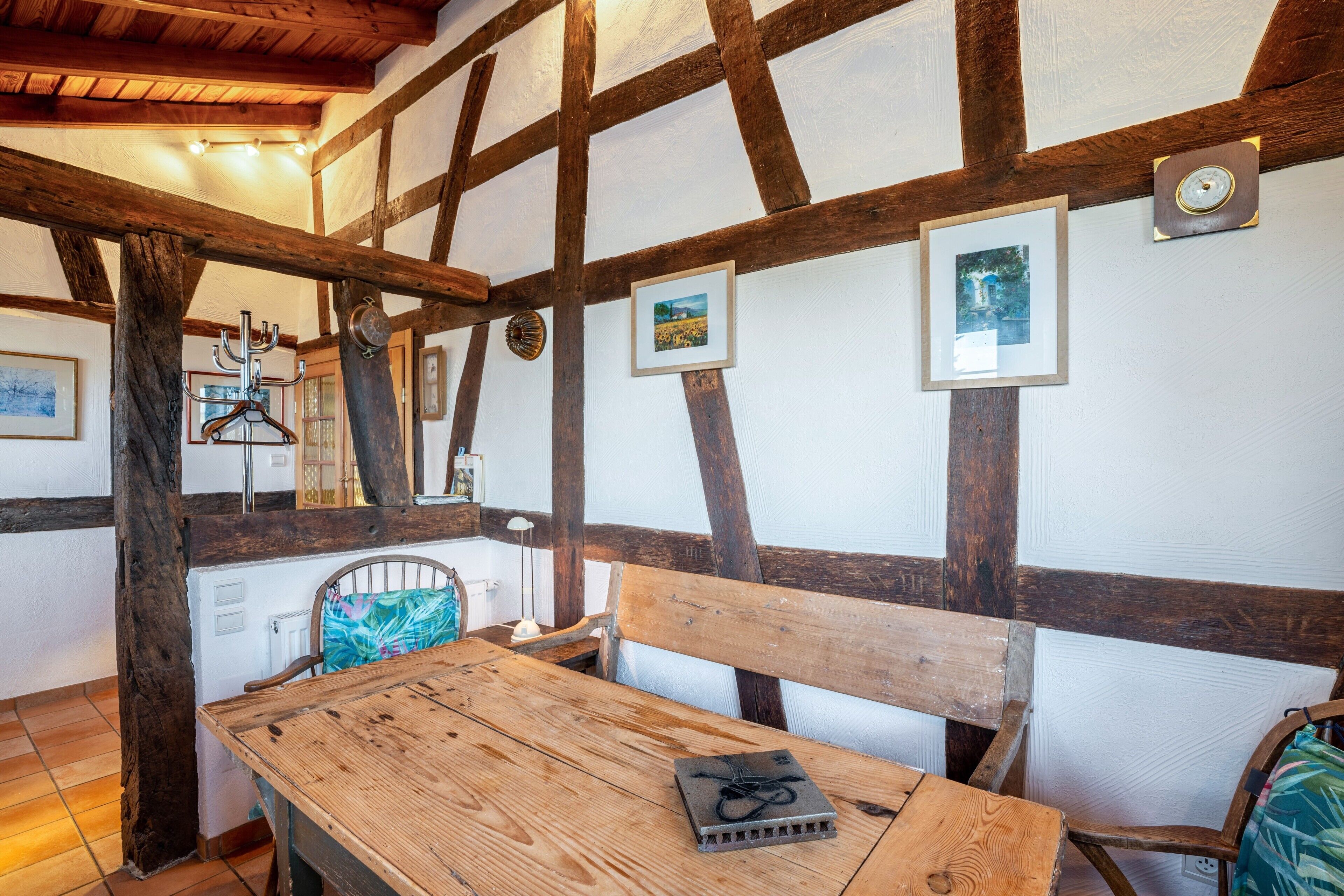 A rustic room with exposed wooden beams, a wooden table, and a bench.