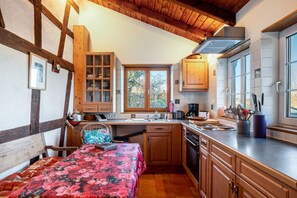 A compact kitchen with wooden cabinets, a dining table, and a window providing natural light.