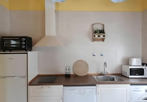 Uma cozinha equipada com micro-ondas, torradeira, máquina de lavar louça e pia.