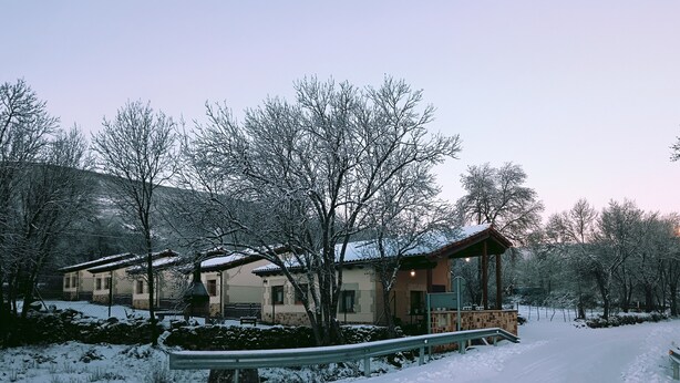 A snow-covered landscape with a row of buildings, a covered walkway, and a pathway. - Peaceful Rural House in Soria with Private Garden and Nature (Aldehuela del Rincón)