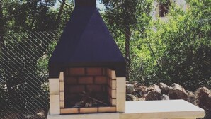 A brick-built outdoor grill with a chimney, placed on a wooden table. - Peaceful Rural House in Soria with Private Garden and Nature (Aldehuela del Rincón)