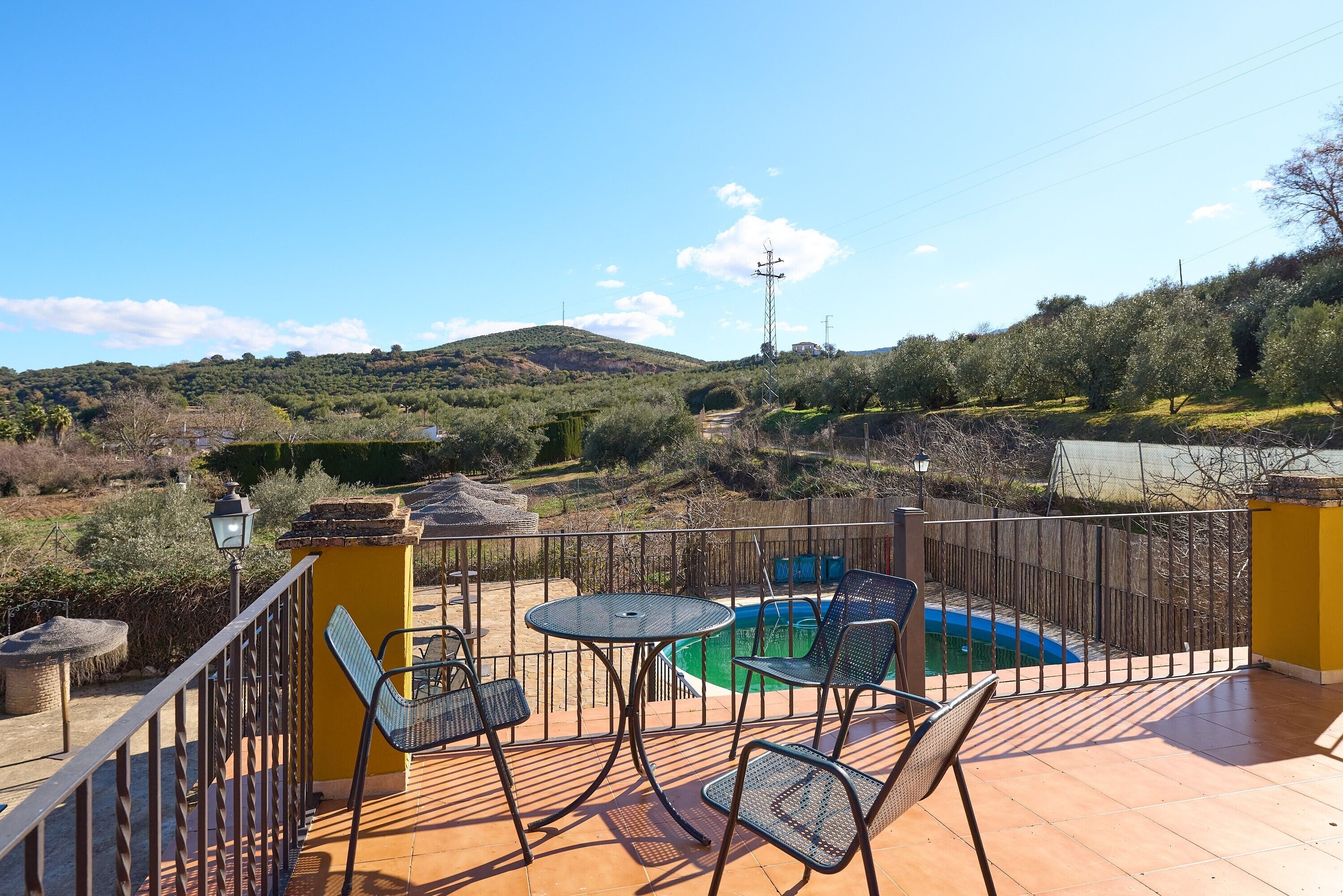 Eine Terrasse mit Pool, Stühlen und Blick auf eine hügelige Landschaft.