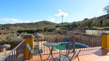 Eine Terrasse mit Pool, Stühlen und Blick auf eine hügelige Landschaft.