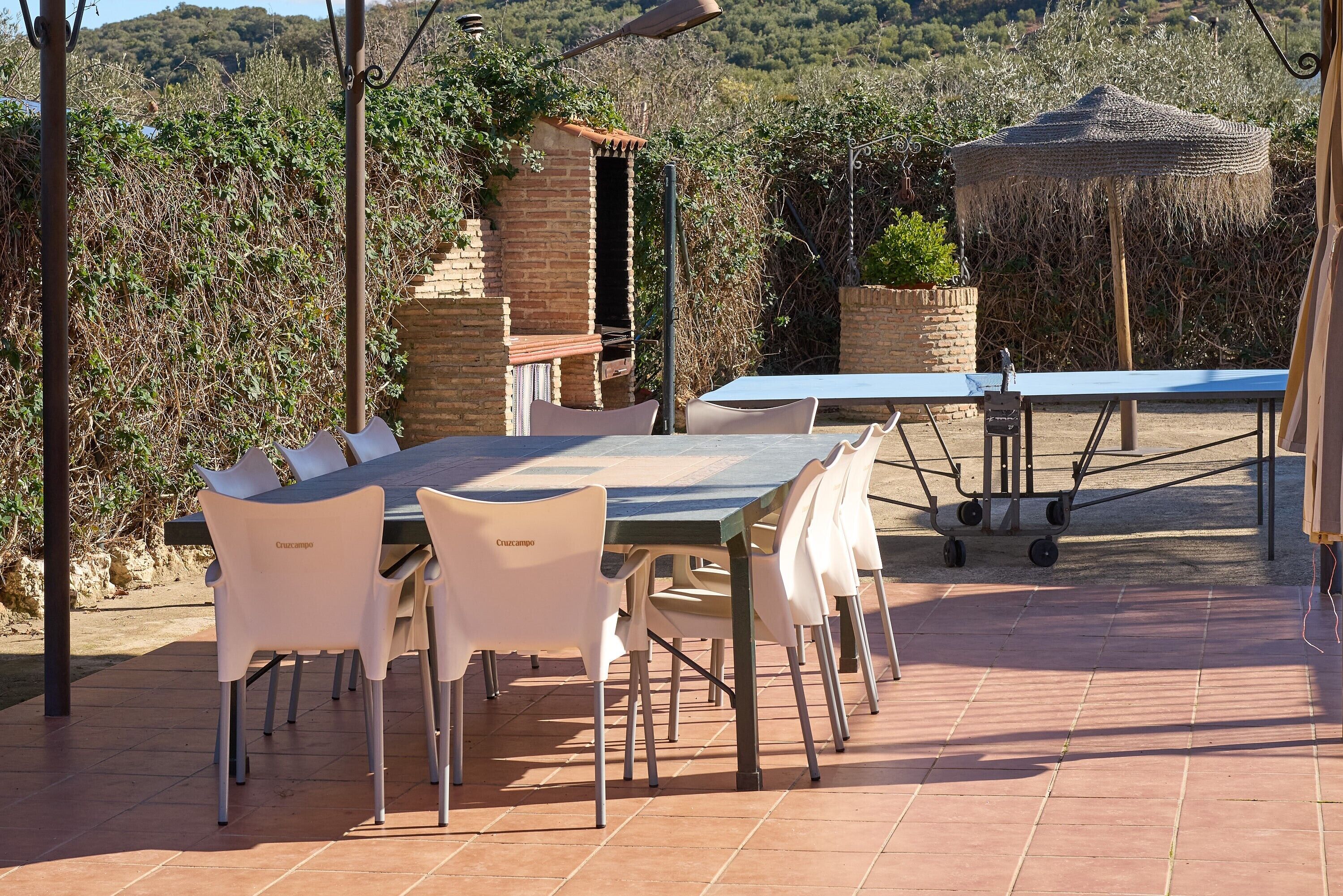 Un espacio de comedor al aire libre con un horno de ladrillo, una mesa con sillas y una pérgola.