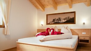Een houten bed met een wit matras, een nachtkastje, een wandlamp en een lijst met een foto erboven.
