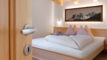 Una habitación de hotel con techo de madera, una cama con ropa blanca y un cuadro en la pared.