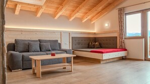 Een modern interieur met een houten plafond, een bank, een bed en een raam met uitzicht.