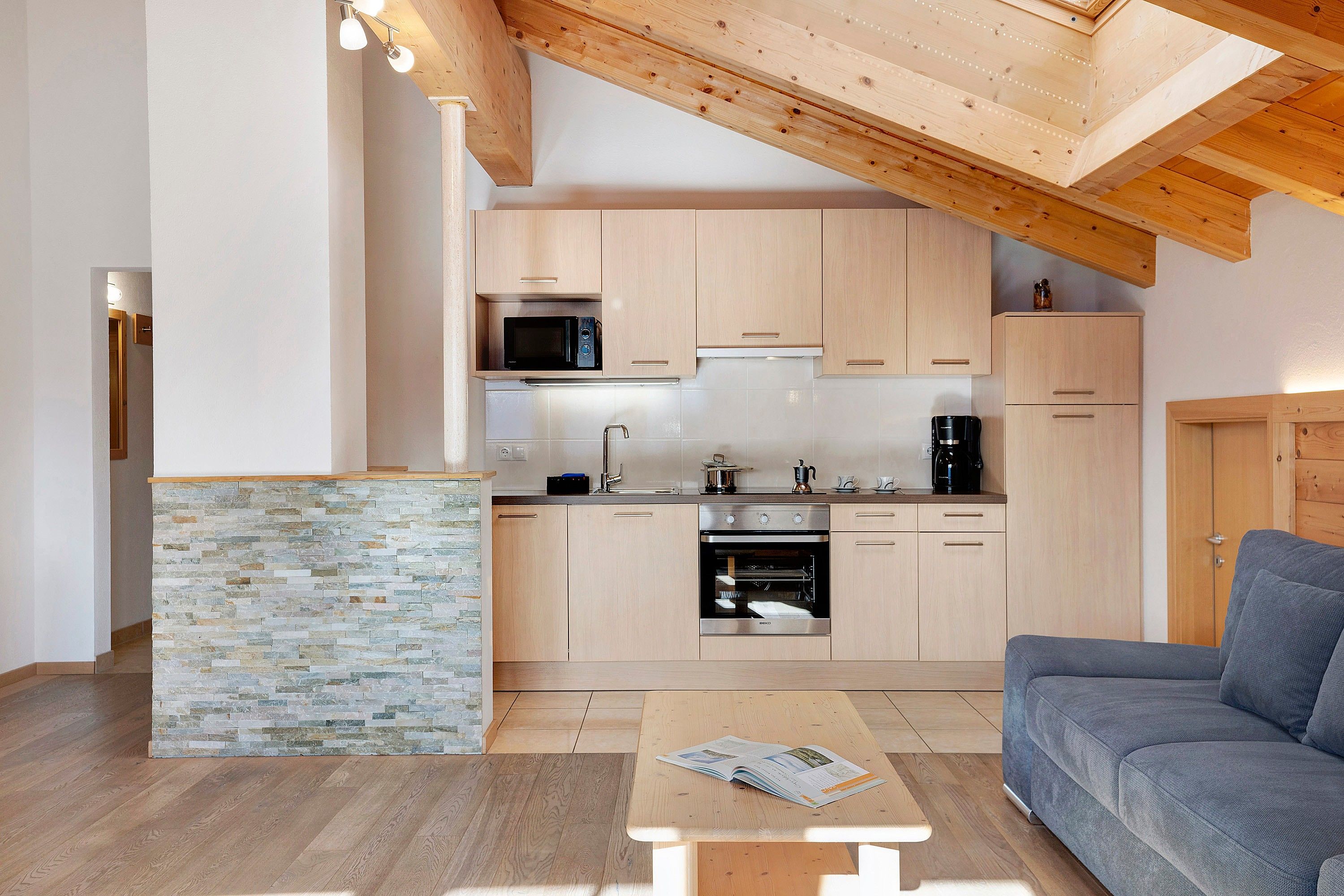 Una cocina moderna con armarios de madera, microondas integrado y horno de acero inoxidable.