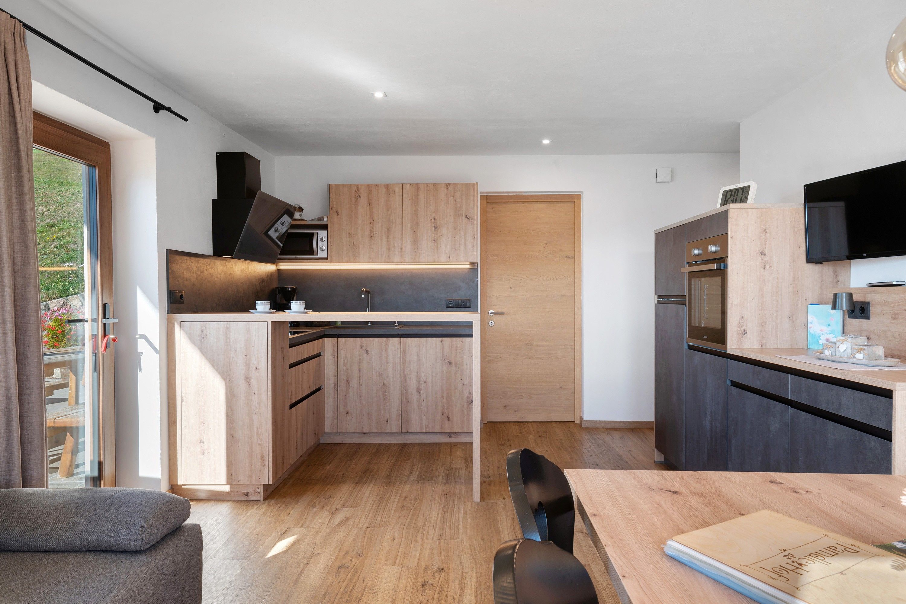 Una cocina moderna con armarios de madera, horno integrado y comedor con mesa y sillas.