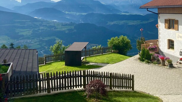 Une maison avec un toit rouge, une clôture en bois et un jardin fleuri.