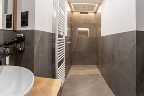 Un baño moderno con ducha, lavamanos y espejo.