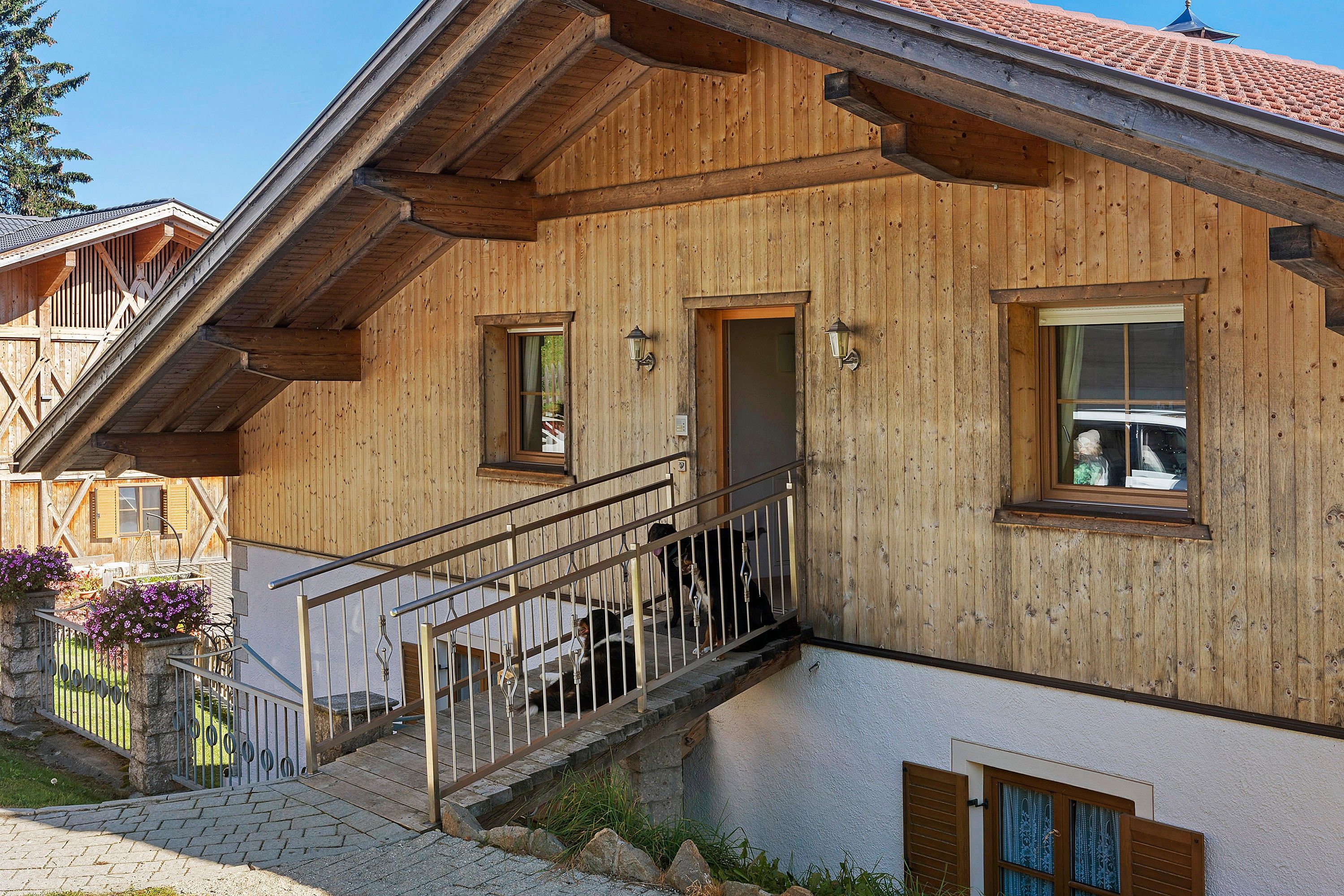 A wooden chalet with a balcony, a staircase, and a window with a view.