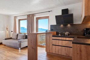 A modern kitchen with wooden cabinets, a built-in stove, and a flat-screen TV mounted above it. - Apartment 'Schönblick' with Mountain View, Private Terrace and Wi-Fi (Villanders)