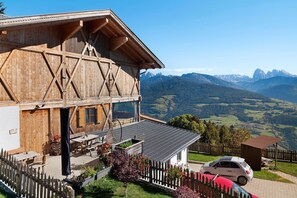 A wooden chalet with a balcony overlooking a mountainous landscape.