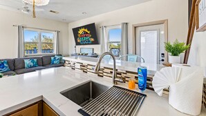 A modern kitchen with a central island, a sink, and a chandelier. - Relaxing Beach Escape w/ Private Decks Walk2Beach (Galveston)