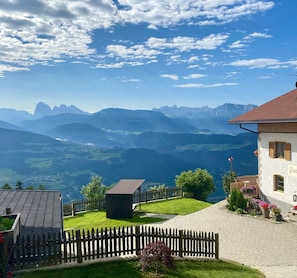 Une maison avec un toit rouge, une clôture en bois et une vue sur les montagnes.