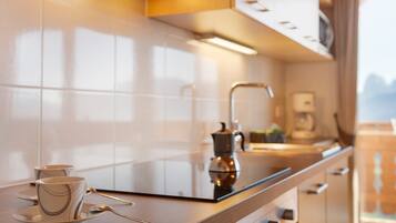 Una cocina moderna con encimera de vidrio, cafetera y vistas a las montañas.