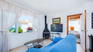 Un salon avec un canapé, un téléviseur, une cheminée et une vue sur l’extérieur.