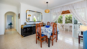 Un espace repas comprenant une table, des chaises, un miroir et une vue sur l’extérieur.