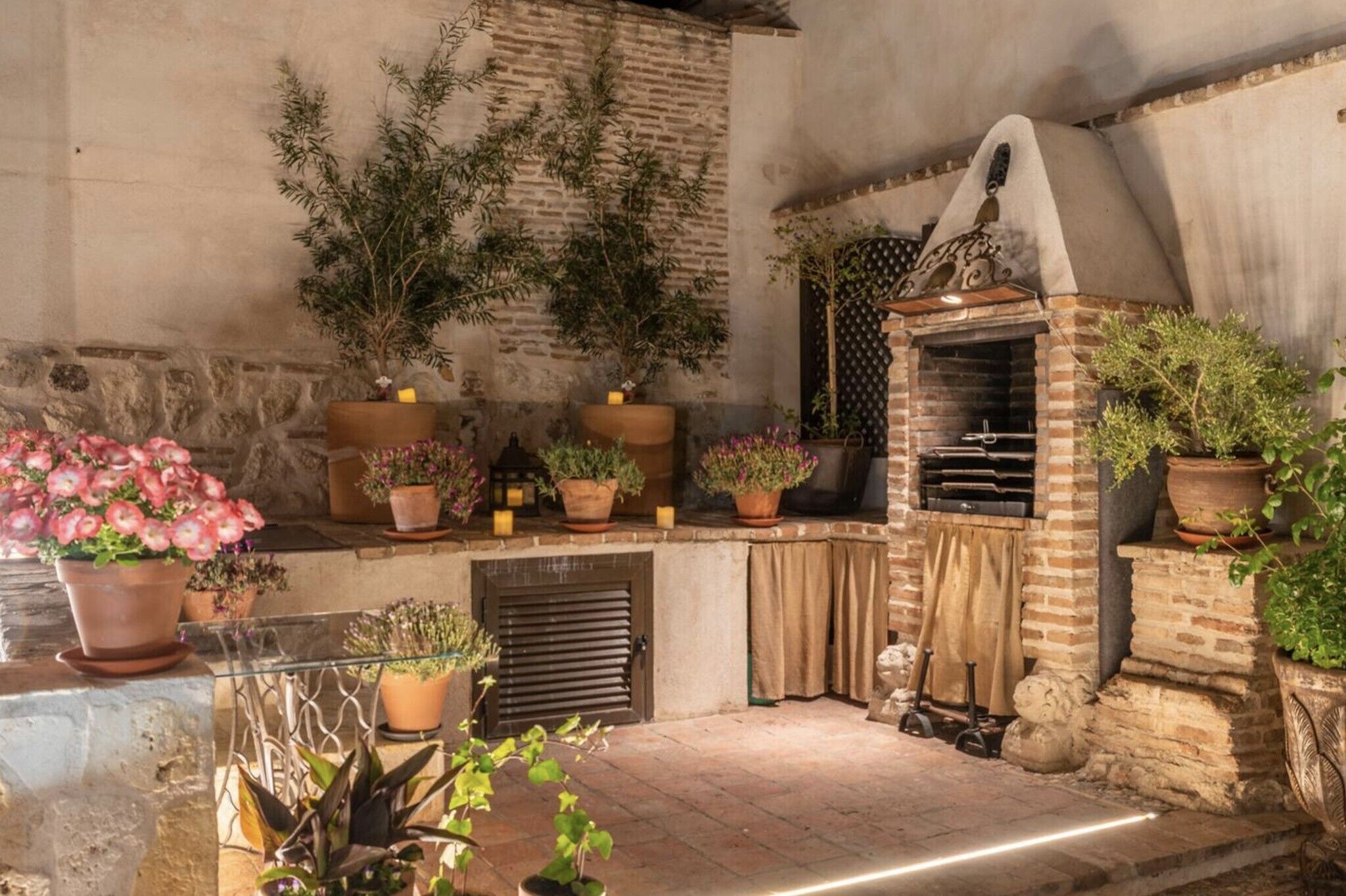 Une terrasse extérieure avec un four en briques, des plantes en pot et un mur en pierre.