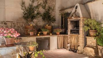 Une terrasse extérieure avec un four en briques, des plantes en pot et un mur en pierre.