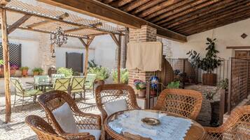 An outdoor patio with wicker furniture, a brick fireplace, and potted plants.