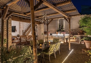 Une terrasse extérieure dotée d’une pergola en bois, d’une table avec des chaises et d’un mur en pierre.