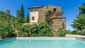 Un bâtiment en pierre avec une piscine devant.
