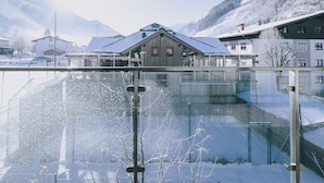 A snow-covered mountain landscape with a wooden building featuring a sloped roof. - Apartments Goldbergblick - TOP 1, Balcony & Mountain view (Rauris)