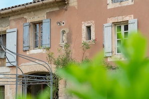 A building with multiple windows, some with shutters, and a statue in one window.