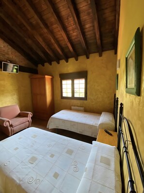 Quarto com duas camas, um guarda-roupa de madeira, uma cadeira rosa e uma janela com luz natural.