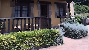A two-story building with a balcony, a chimney, and a garden with bushes. - Country House 'Los Avellanos 2' with Mountain Views, Private Terrace and Garden (Celis)