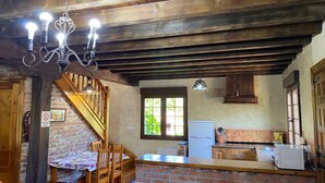 A rustic kitchen with a brick wall, wooden ceiling beams, and a dining area with a table and chairs. - Country House 'Los Avellanos 2' with Mountain Views, Private Terrace and Garden (Celis)