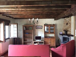 Uma sala de estar com lareira, estantes de madeira, televisão e sofá vermelho.