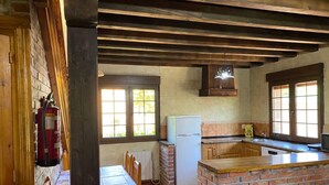 A rustic kitchen with a brick island, wooden ceiling beams, and a window with a view. - Country House 'Los Avellanos 2' with Mountain Views, Private Terrace and Garden (Celis)