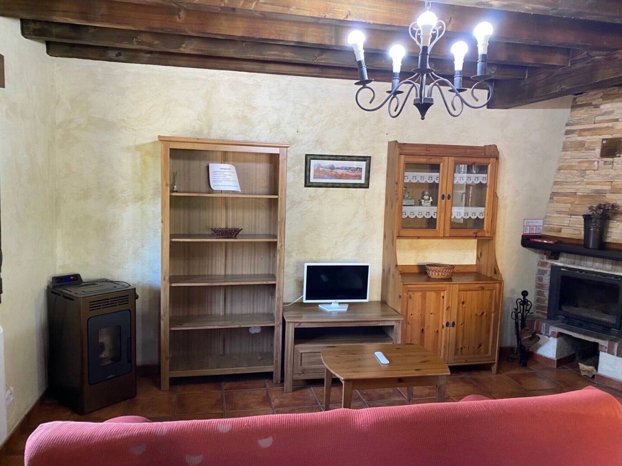 Un salon avec une cheminée, des meubles en bois, un téléviseur et un lustre.