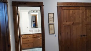 Una habitación con un armario de madera, un espejo con iluminación y un lavabo con alacenas.