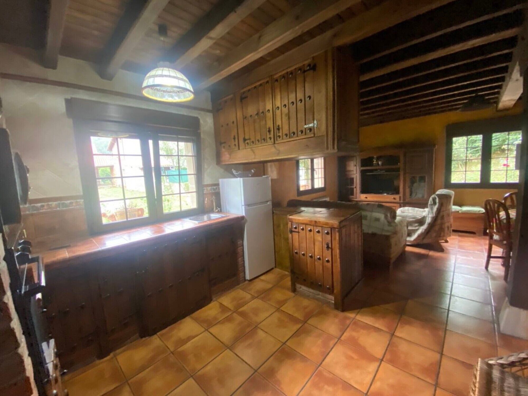 Una cocina con armarios de madera, un refrigerador y una ventana.
