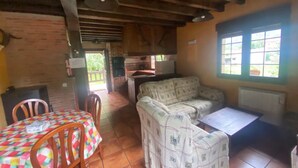A rustic interior with a dining table, chairs, a sofa, and a window with a view.