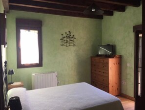A bedroom with a bed, a dresser, a radiator, a window, and a wall decoration.
