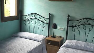 A room with two beds, a nightstand, a lamp, a painting, and a window.