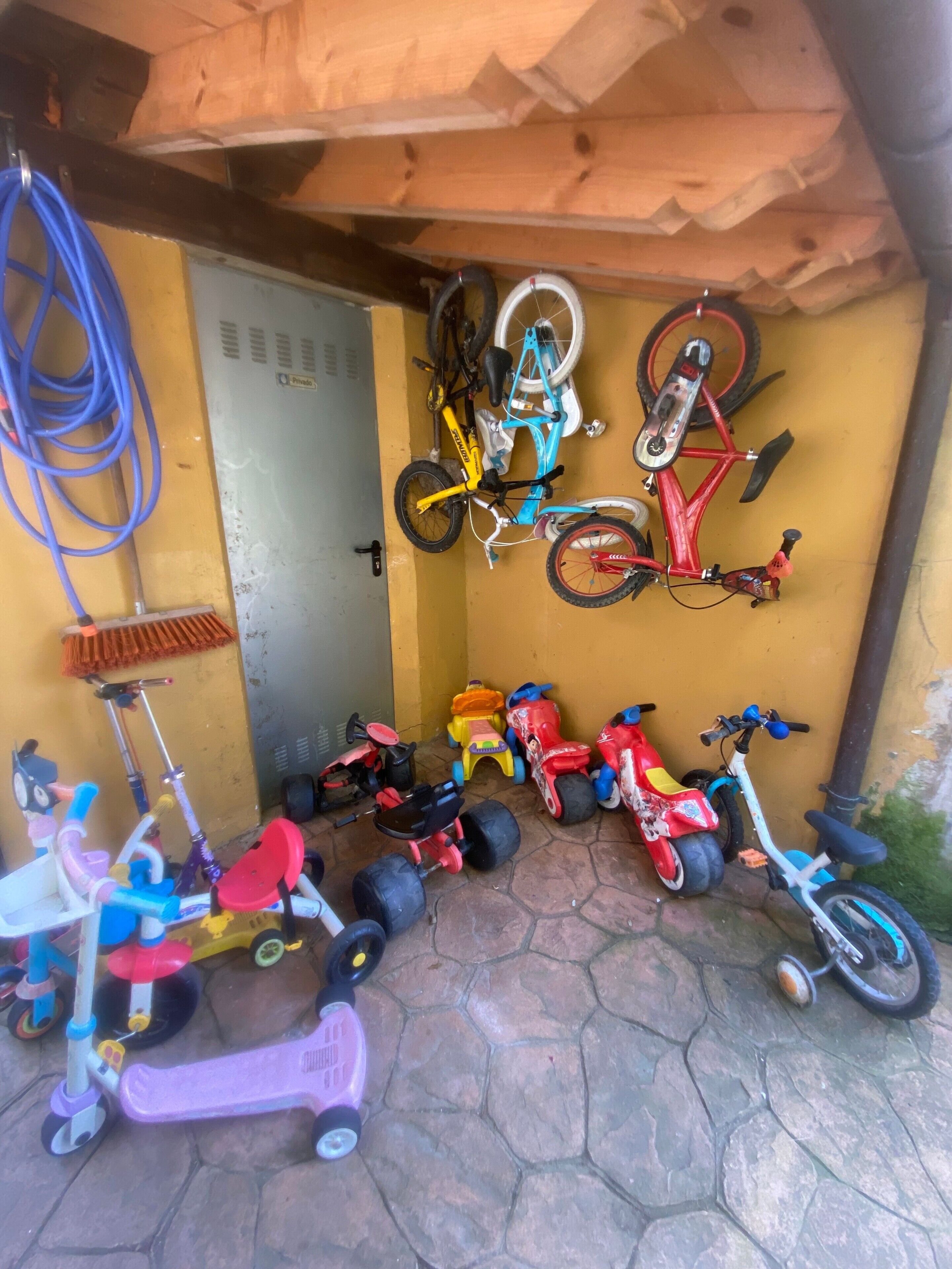 Een overdekt buitengebied met verschillende kinderfietsen en loopfietsen.