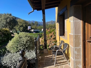 Un immeuble à la façade jaune, doté d’un balcon avec des chaises et offrant une vue sur les montagnes.
